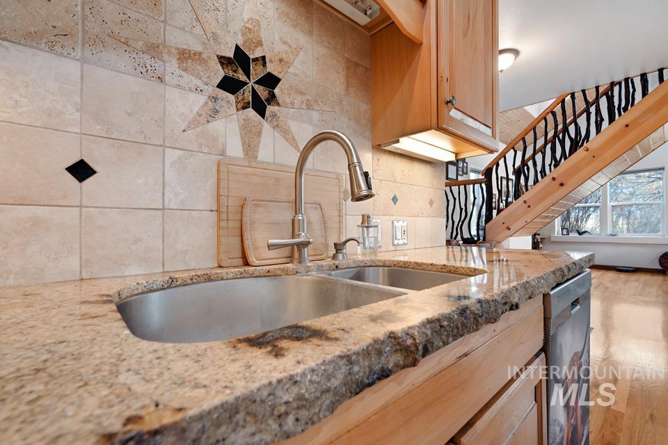7025 Bluebird Lane Sweet, ID 83670 - Photo 19 of 46 Kitchen featuring light brown cabinetry, light stone counters, stainless steel dishwasher, and light wood-style flooring