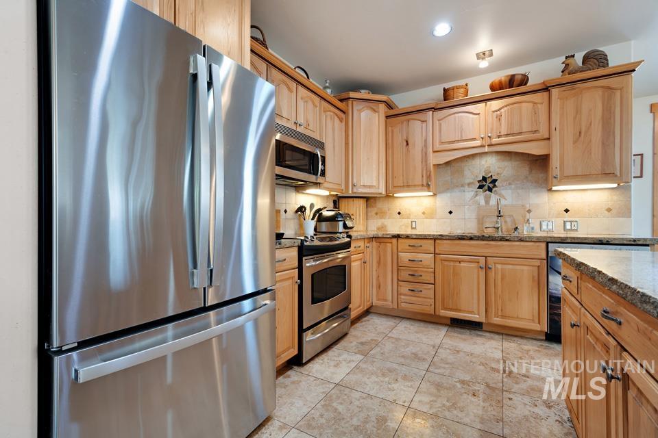 7025 Bluebird Lane Sweet, ID 83670 - Photo 20 of 46 Kitchen featuring stainless steel appliances, light brown cabinets, dark stone countertops, recessed lighting, and tasteful backsplash