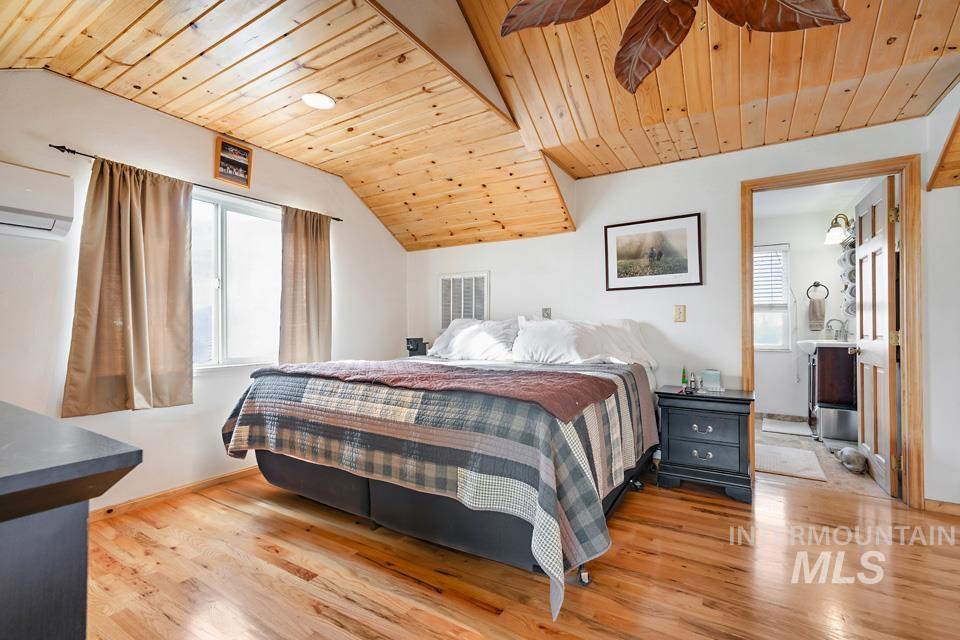 7025 Bluebird Lane Sweet, ID 83670 - Photo 24 of 46 Bedroom featuring wooden ceiling, light wood-style floors, multiple windows, vaulted ceiling, and a wall unit AC