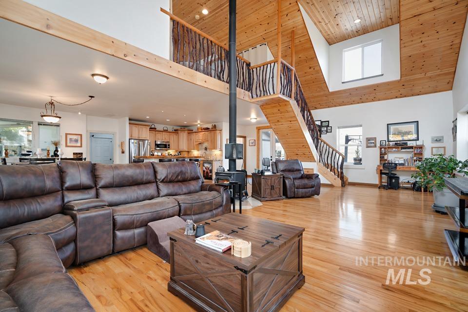 7025 Bluebird Lane Sweet, ID 83670 - Photo 10 of 46 Living room featuring light wood-style floors, stairway, wooden ceiling, a high ceiling, and a wood stove