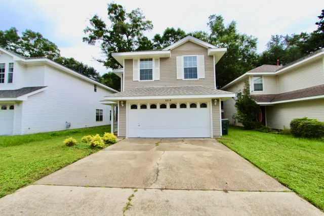 a view of a house with a yard and potted plants