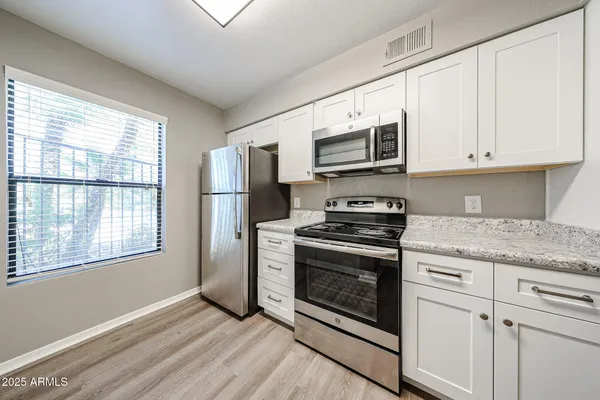 a kitchen with stainless steel appliances granite countertop a stove a microwave and a white cabinets