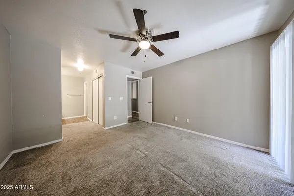 an empty room with windows and fan