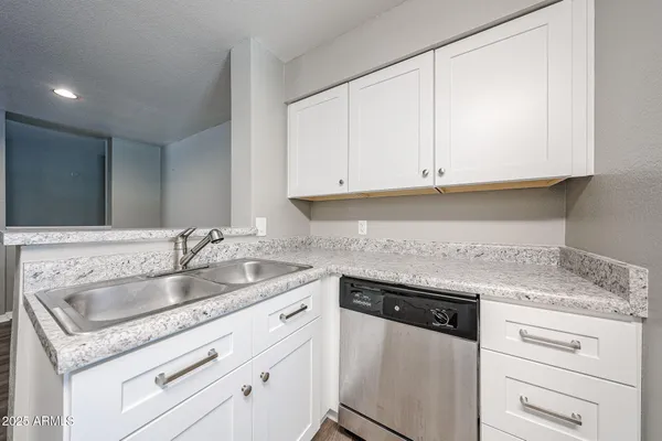 a kitchen with granite countertop white cabinets and a sink