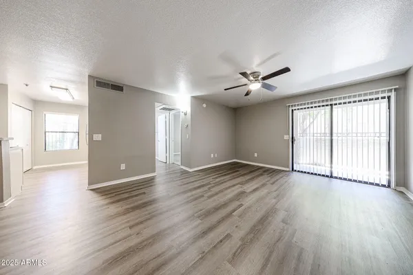 a view of empty room with wooden floor and fan