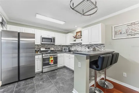 a kitchen with kitchen island granite countertop a stove a sink dishwasher a refrigerator and a dining table with wooden floor