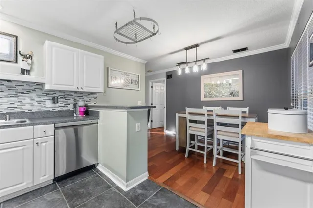 a kitchen with stainless steel appliances granite countertop a stove top oven a sink a dining table and chairs with wooden floor