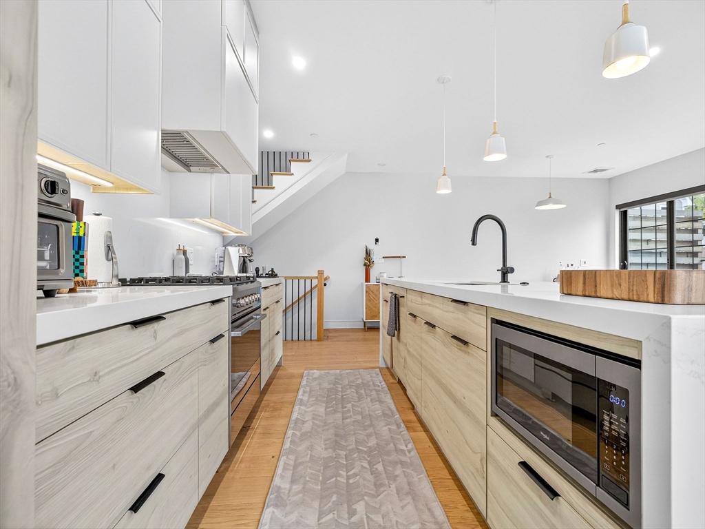 4 Payne Street, Unit FIVE Boston, MA 02122 - Photo 12 of 38 a large white kitchen with stainless steel appliances granite countertop a stove and a sink