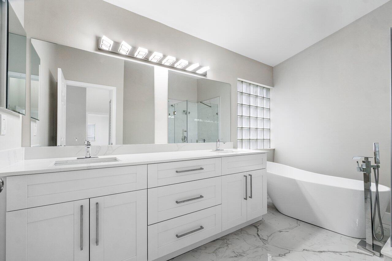7809 Travelers Tree Drive Boca Raton, FL 33433 - Photo 20 of 33 a bathroom with a bathtub a double vanity sink and mirror