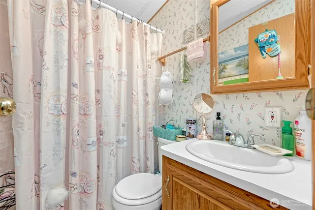 a bathroom with a granite countertop sink a toilet and a shower curtain