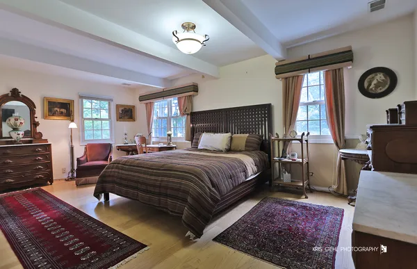 a bedroom with a bed a chandelier with dresser and mirror
