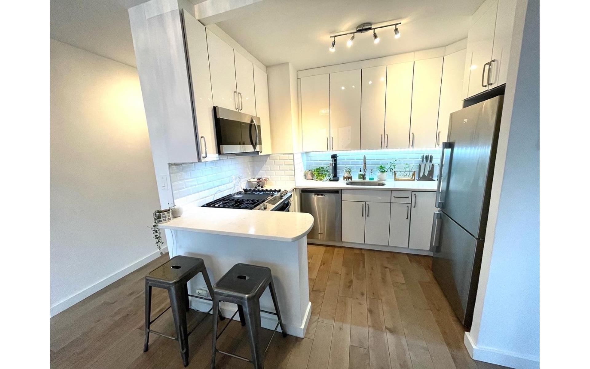 200 East 61st Street, Unit 20A Manhattan, NY 10065 - Photo 6 of 10 a kitchen with a sink a refrigerator a stove a dining table and chairs