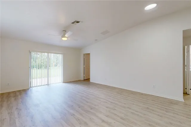 an empty room with wooden floor cabinet and windows