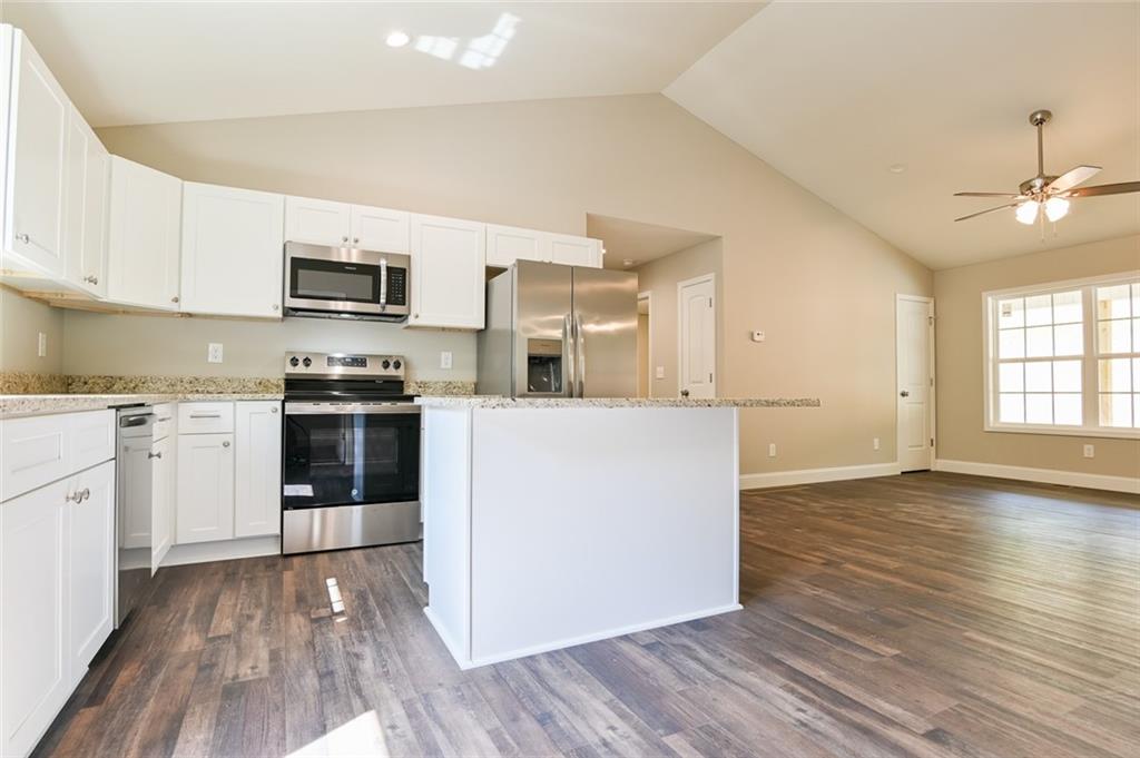 205 Perkins Road Dahlonega, GA 30533 - Photo 4 of 51 a kitchen with stainless steel appliances granite countertop a stove top oven a sink dishwasher and a refrigerator with wooden floor
