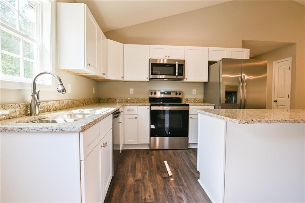 205 Perkins Road Dahlonega, GA 30533 - Photo 5 of 51 a kitchen with stainless steel appliances granite countertop a stove top oven a sink dishwasher and white cabinets with wooden floor