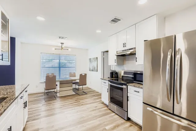 a kitchen with granite countertop a refrigerator stove top oven and sink