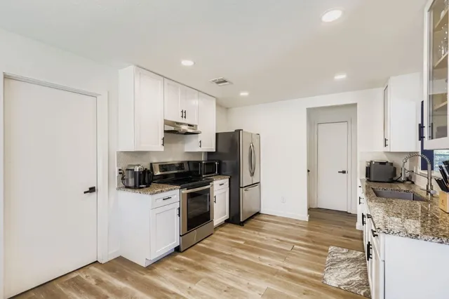 a kitchen with stainless steel appliances granite countertop a refrigerator stove microwave and sink