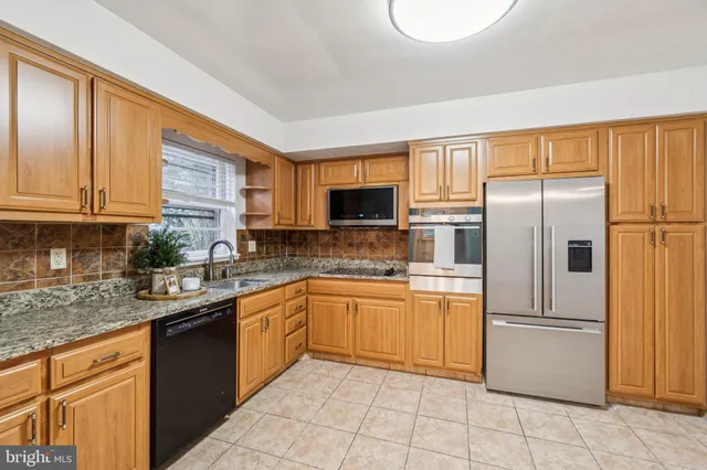 a kitchen with stainless steel appliances granite countertop a refrigerator stove top oven and sink