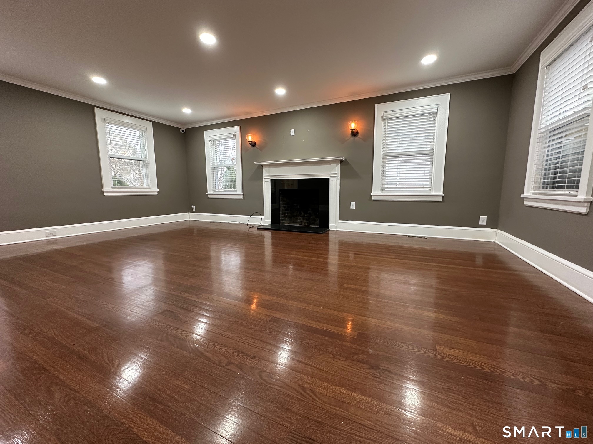 an empty room with wooden floor fireplace and windows