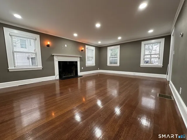 an empty room with wooden floor fireplace and window