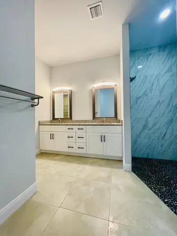 a bathroom with a granite countertop sink a mirror and shower
