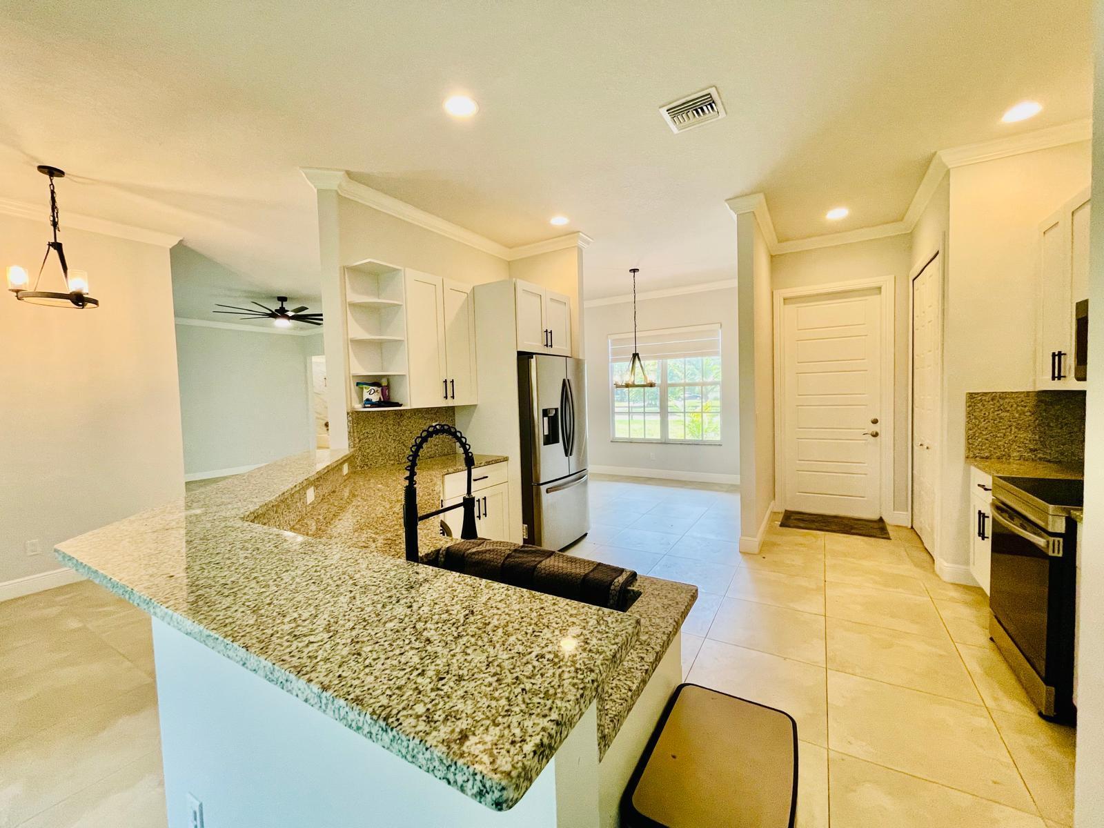 17225 78th Road North Loxahatchee, FL 33470 - Photo 46 of 93 a kitchen with kitchen island granite countertop a sink stove and refrigerator