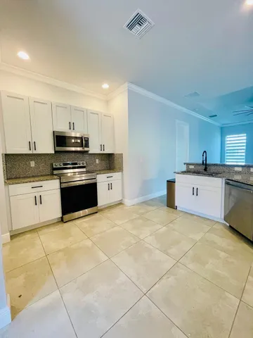 a kitchen with stainless steel appliances granite countertop a stove a sink and a white cabinets