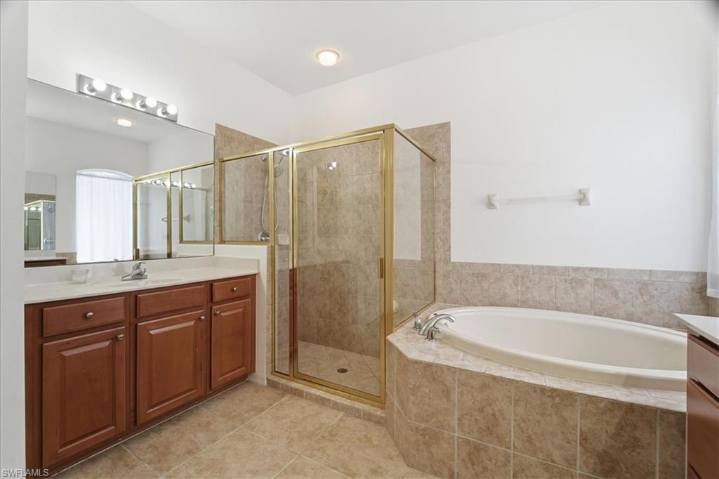 14439 Manchester Drive Naples, FL 34114 - Photo 8 of 47 a spacious bathroom with a granite countertop sink a mirror a bathtub and shower