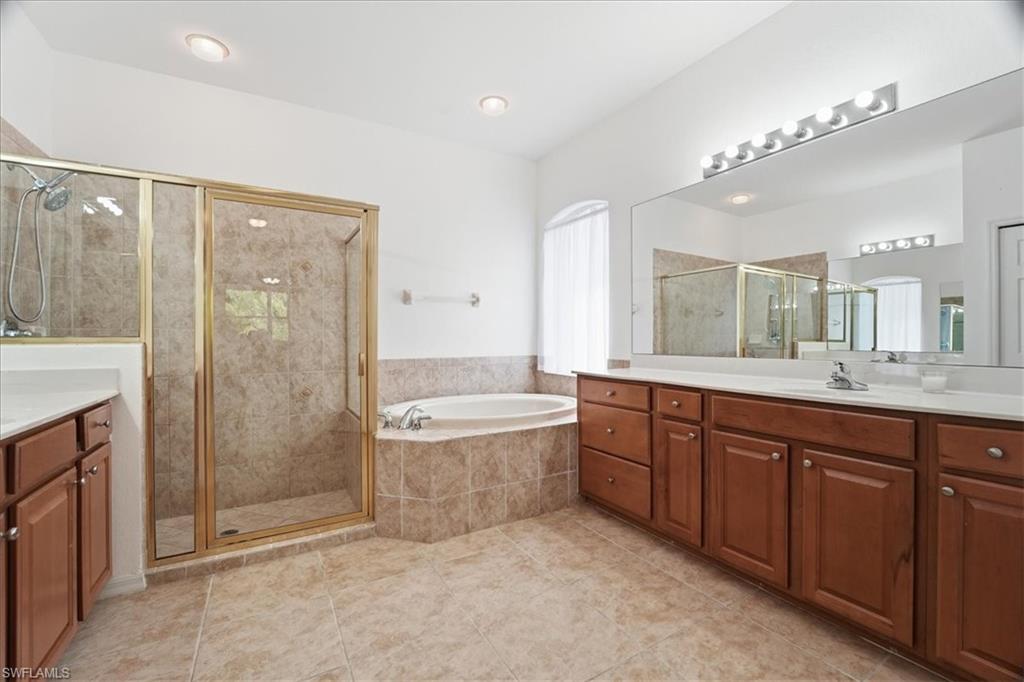 14439 Manchester Drive Naples, FL 34114 - Photo 9 of 47 a spacious bathroom with a granite countertop sink a mirror a bathtub and shower