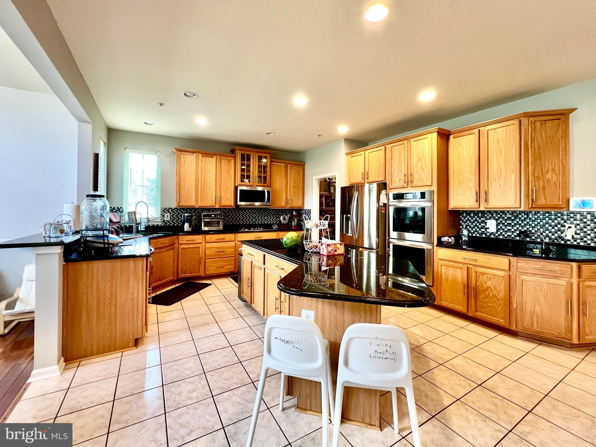 13501 Oaklands Manor Drive Laurel, MD 20708 - Photo 22 of 46 a large living room with stainless steel appliances kitchen island granite countertop a large kitchen island a stove a sink a dining table and chairs