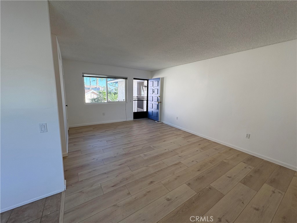 17061 Evergreen Circle, Unit D Huntington Beach, CA 92647 - Photo 2 of 18 an empty room with wooden floor and windows