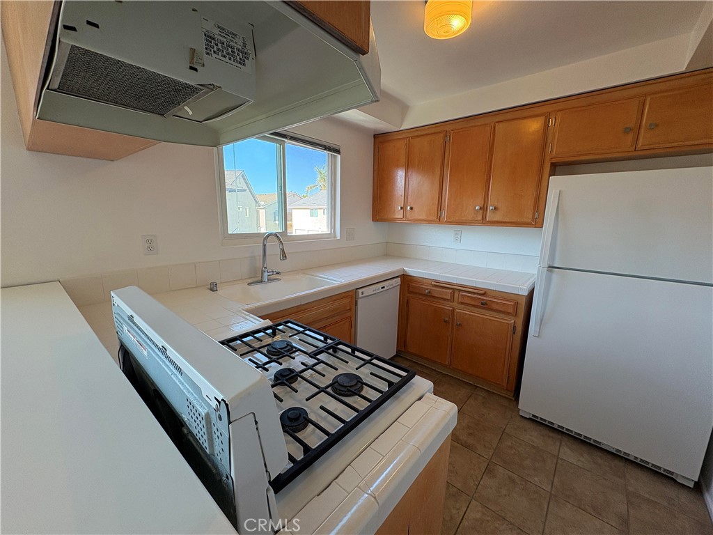 17061 Evergreen Circle, Unit D Huntington Beach, CA 92647 - Photo 4 of 18 a kitchen with sink a refrigerator and a stove top oven