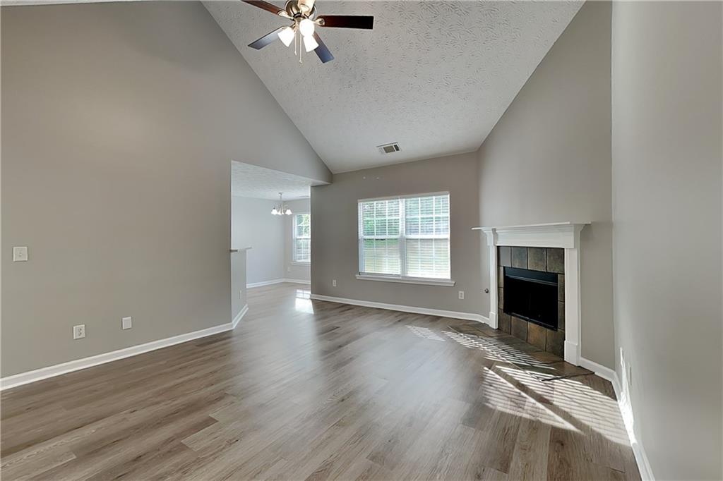 6345 Aarons Way Flowery Branch, GA 30542 - Photo 2 of 19 an empty room with wooden floor fireplace and windows