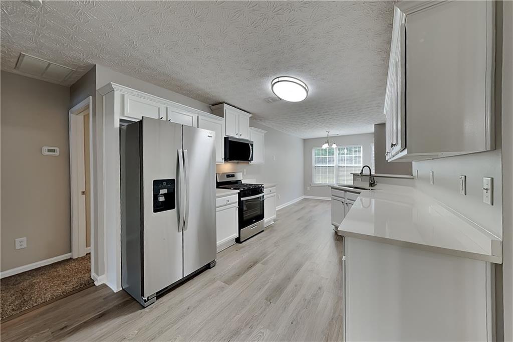 6345 Aarons Way Flowery Branch, GA 30542 - Photo 4 of 19 a kitchen with stainless steel appliances a refrigerator sink and stove