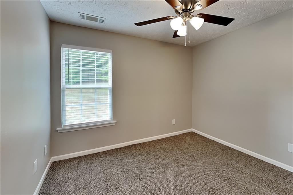 6345 Aarons Way Flowery Branch, GA 30542 - Photo 9 of 19 an empty room with a chandelier fan and windows
