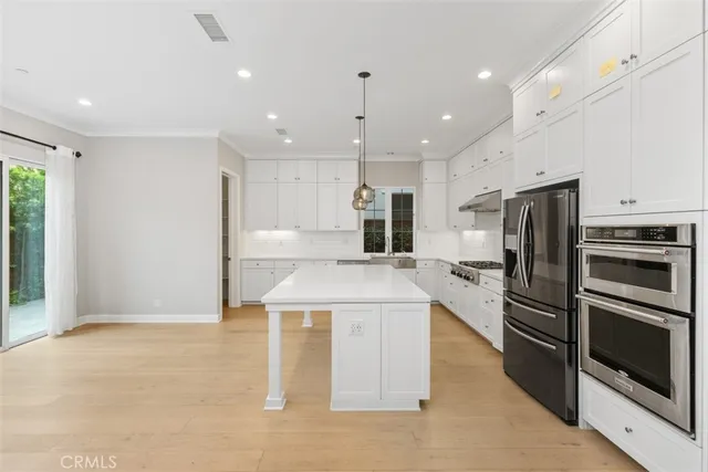 a kitchen with kitchen island a stove a refrigerator and a sink