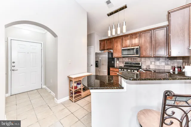 a kitchen with stainless steel appliances granite countertop a sink refrigerator and cabinets