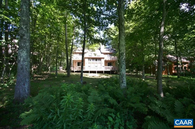 a view of a house with a wooden deck and a floor to ceiling window