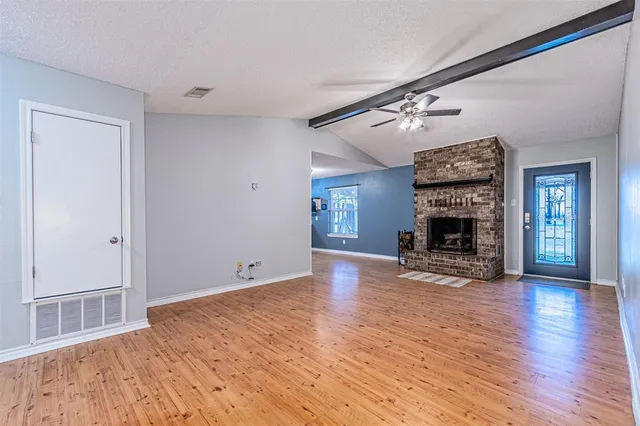 a view of empty room with wooden floor and fireplace