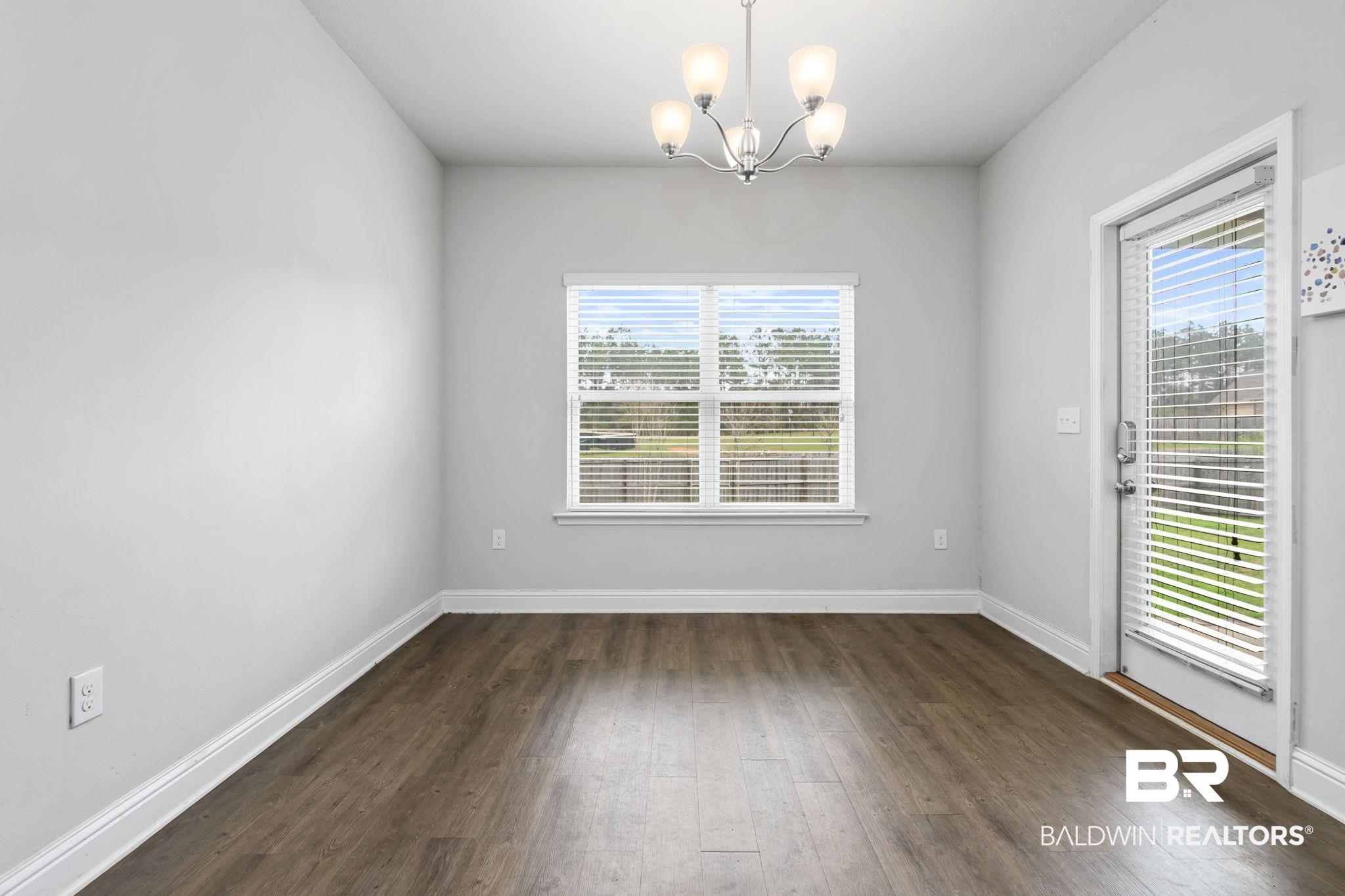 12693 Waxwing Avenue Daphne, AL 36527 - Photo 21 of 43 Unfurnished room featuring a chandelier, dark wood-type flooring, and plenty of natural light