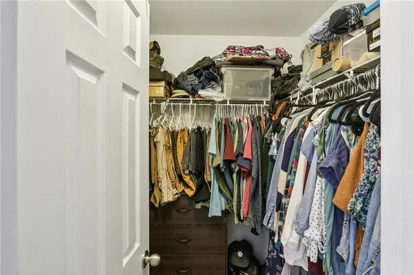 a view of walk in closet with clothes and shoes