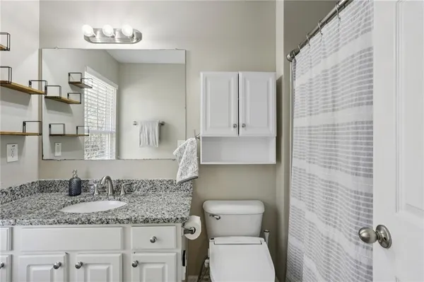 a bathroom with a granite countertop sink a toilet and a mirror