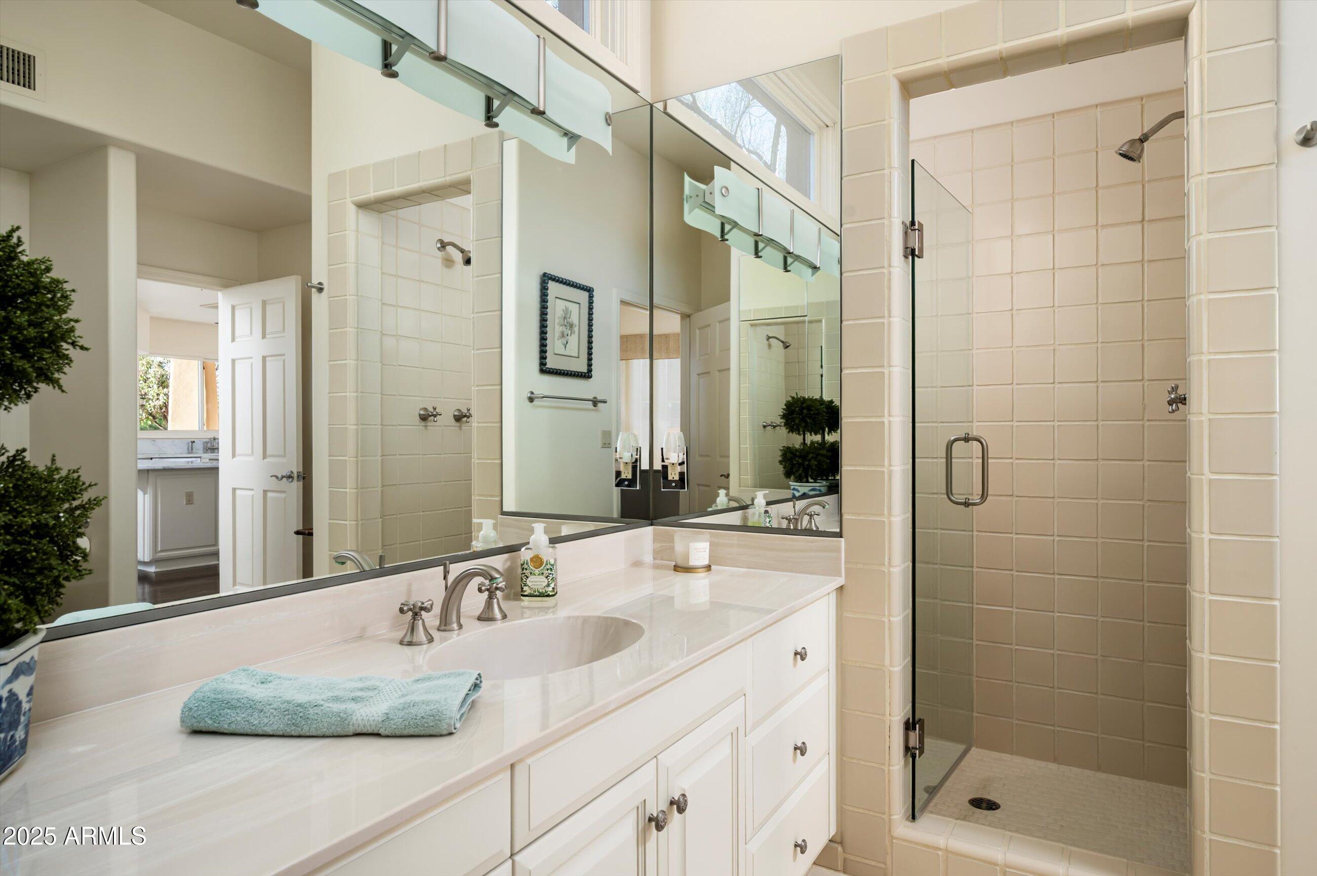 10040 East Happy Valley Road, Unit 274 Scottsdale, AZ 85255 - Photo 34 of 73 a bathroom with a granite countertop sink a mirror a glass door a shower and vanity