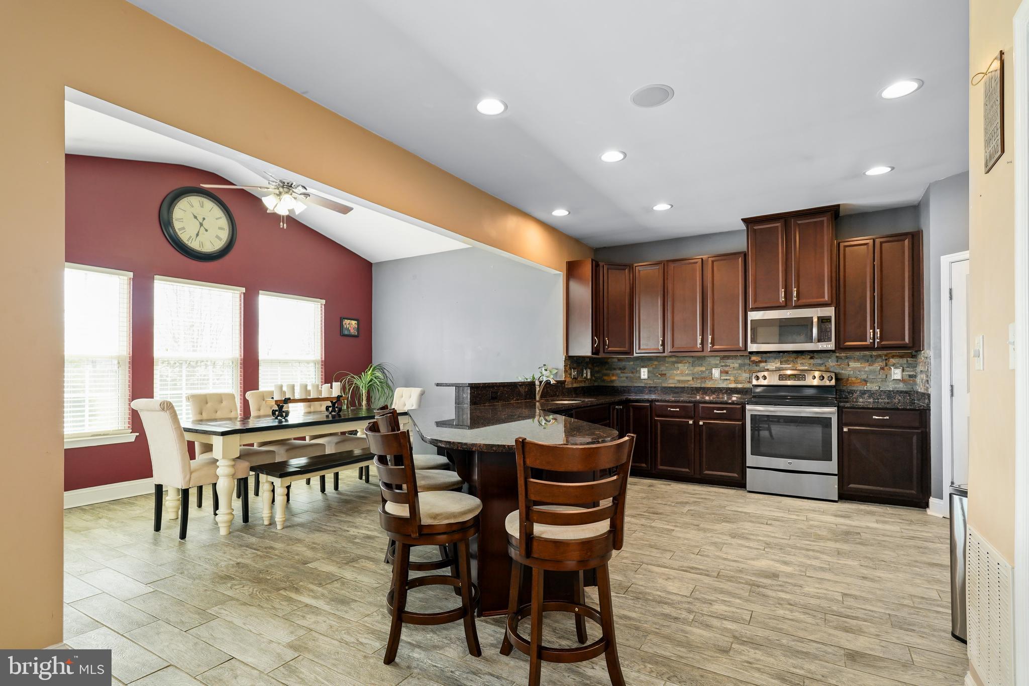 144 Abbigail Crossing Townsend, DE 19734 - Photo 14 of 33 a kitchen with stainless steel appliances granite countertop a stove top oven a sink a dining table and chairs with wooden floor