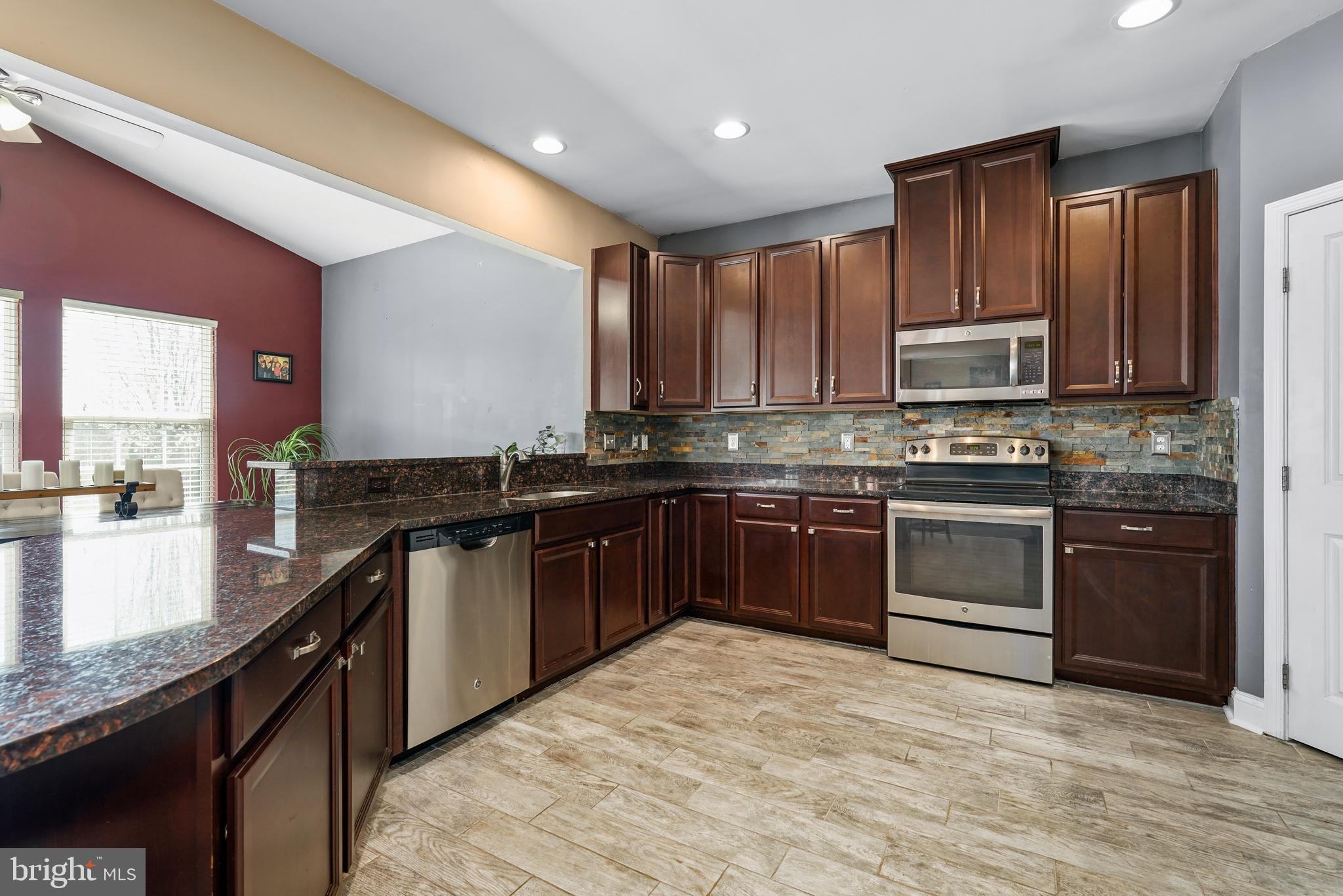 144 Abbigail Crossing Townsend, DE 19734 - Photo 10 of 33 a kitchen with stainless steel appliances granite countertop a stove top oven a sink dishwasher a refrigerator and a microwave