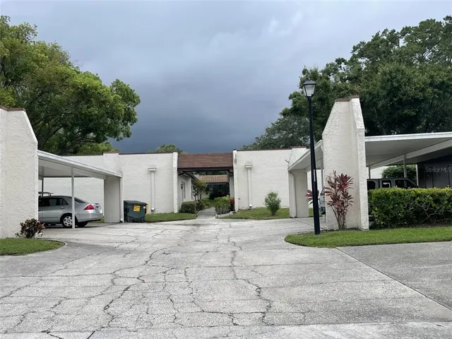 a view of a white house with a yard and large trees