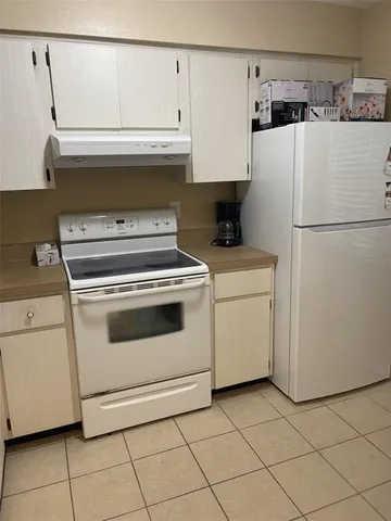 a white refrigerator freezer and a stove sitting inside of a kitchen