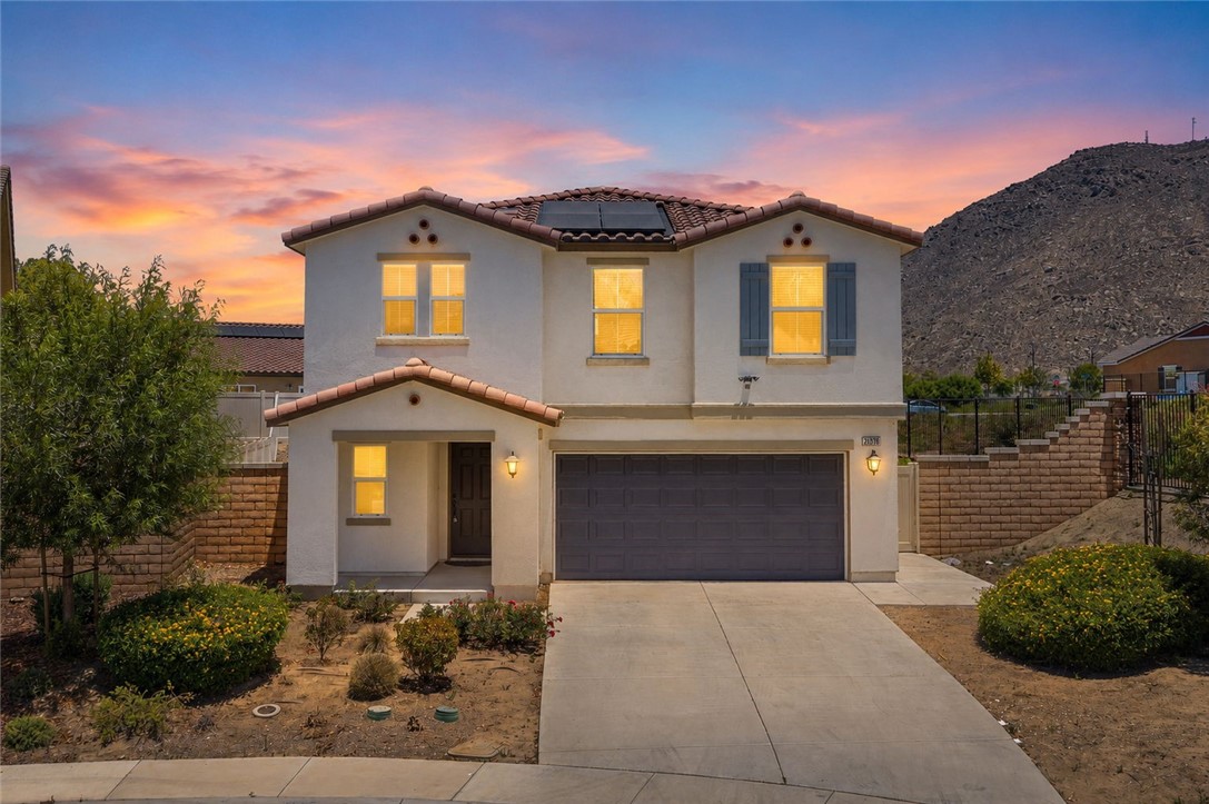 Twilight front exterior with two-car garage, solar panels, and mountain backdrop.