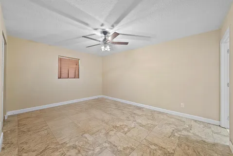 an empty room with a chandelier fan and windows