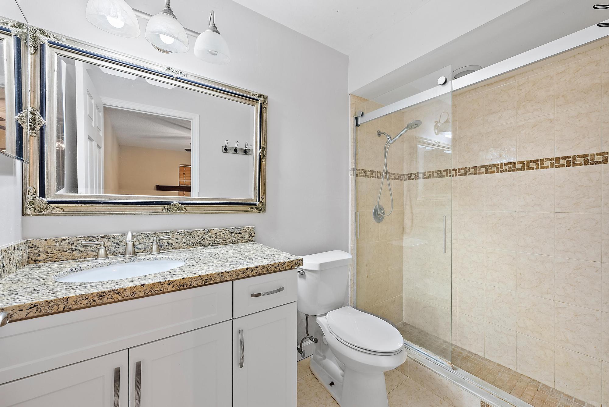 18222 126th Terrace North Jupiter, FL 33478 - Photo 13 of 22 a bathroom with a granite countertop sink toilet mirror and a shower